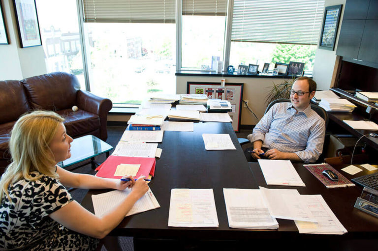 Two attorneys talk at their desk