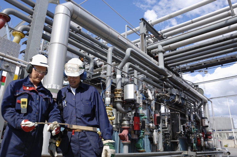 Two men in coveralls and hard hats at work