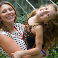 Julie, a mesothelioma survivor, holds her young daughter as they smile together for a photo