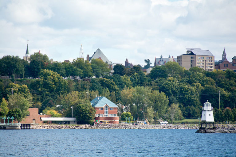 A small white light house and buildings by a lake in Vermont