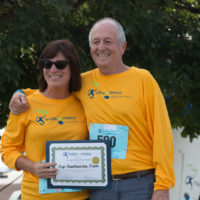 George's family wearing yellow "Miles for Meso" shirts while holding up a certificate that reads "Top Fundraising Team"