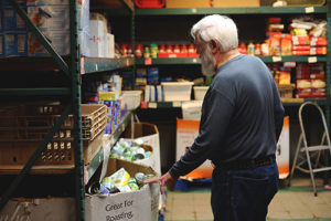 Warehouse Director Les Hahn, who has been a volunteer for five years, gives a tour of the center’s food pantry. He said the firm’s donation of food will help them easily get through the holidays and ensure area families have the food they need.