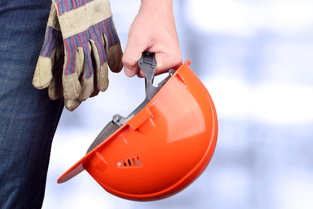 A worker holding an orange hard hat