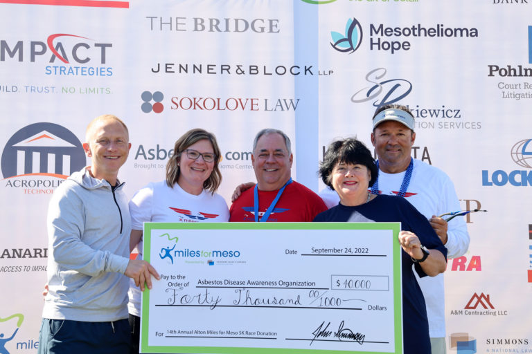 5 people hold a large "Miles for Meso" check awarded in 2022. The check is for $40,000