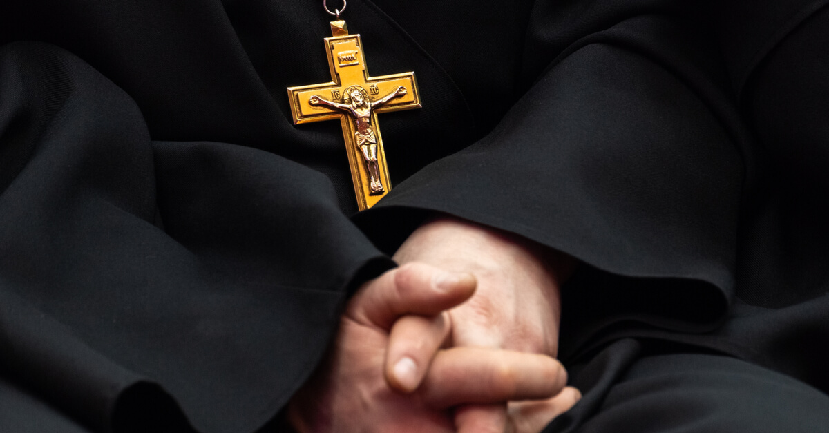 a Catholic priest's hands and a cross