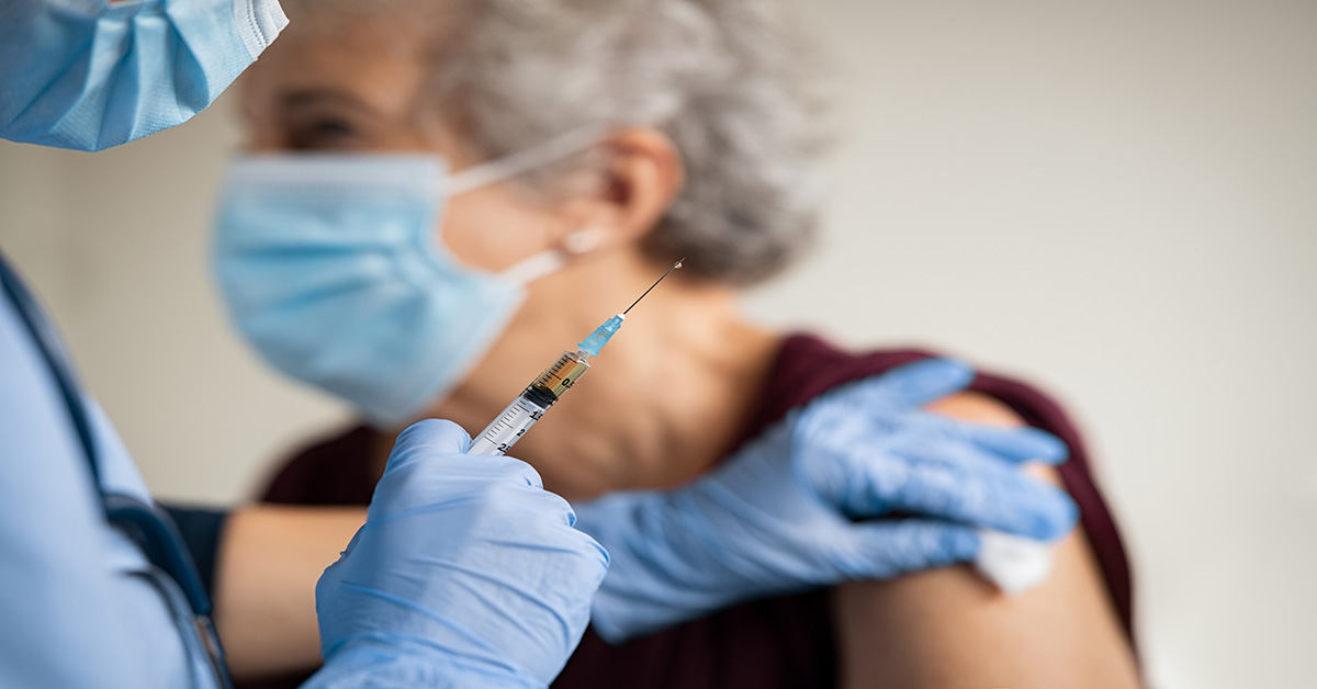 nurse administering a flu shot on an elderly woman