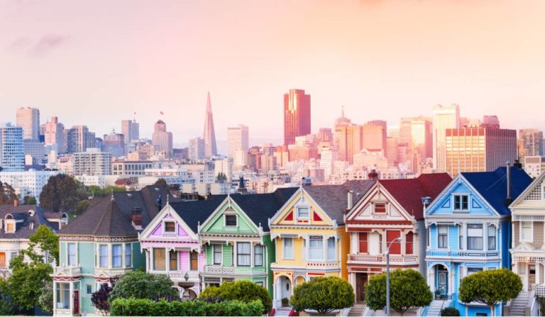 Early evening warm light skyline of San Francisco and painted ladies from Alamo park square