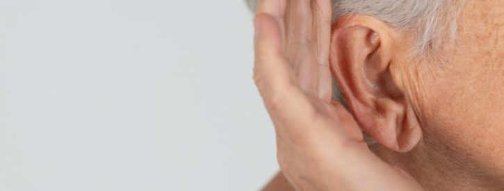 Elderly woman cupping her ear to hear better