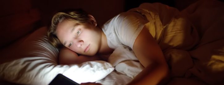 teen boy addicted to social media using his mobile device late into the night