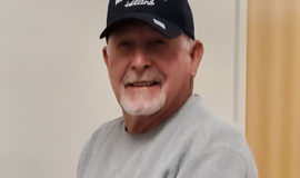 Photo of John Stahl, wearing a black baseball hat and gray sweatshirt