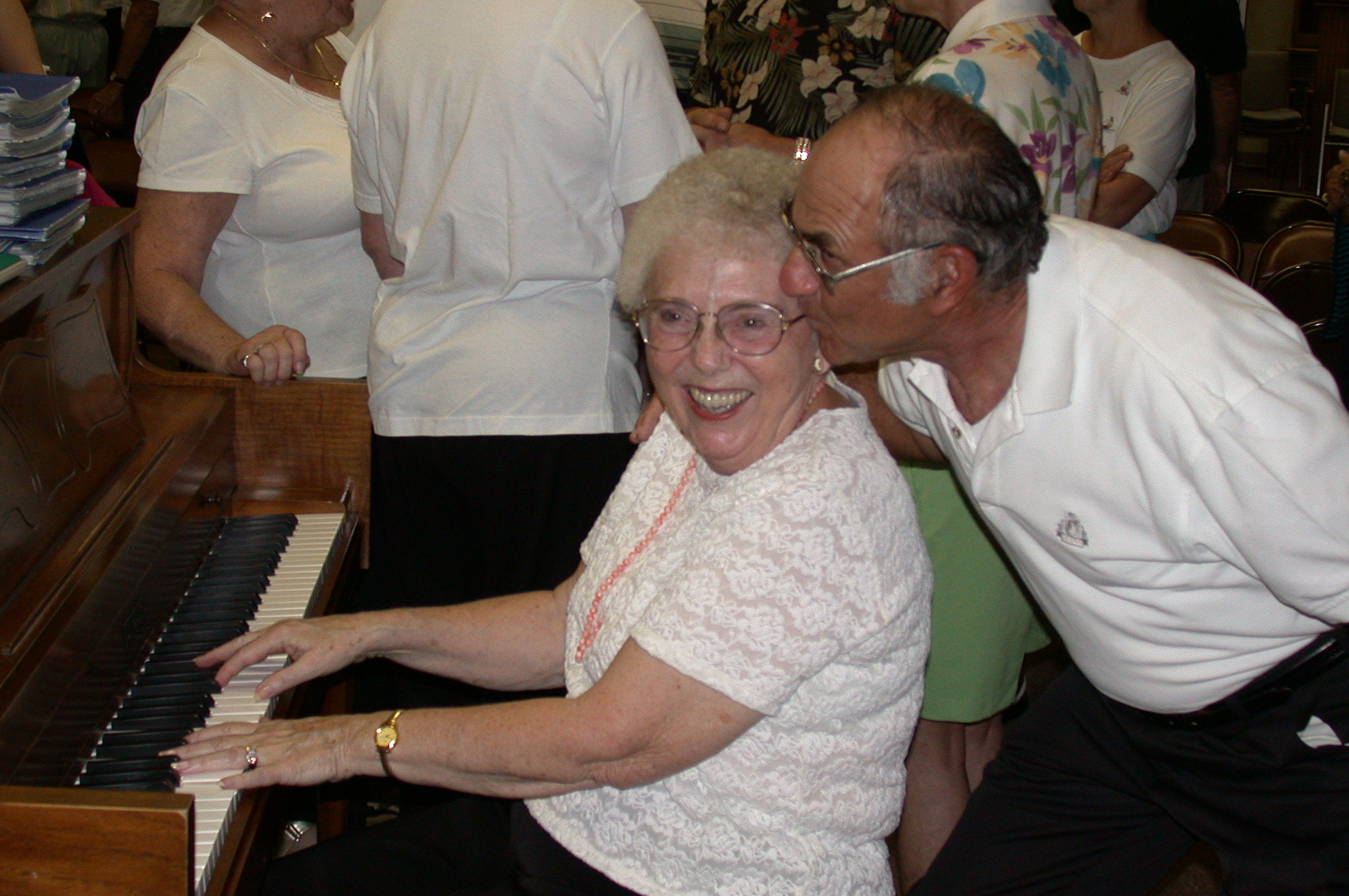 Burlene Jones playing the piano as her husband kisses her cheek