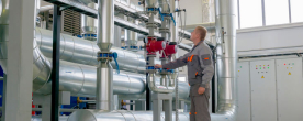 Uniformed worker standing in front of pipes