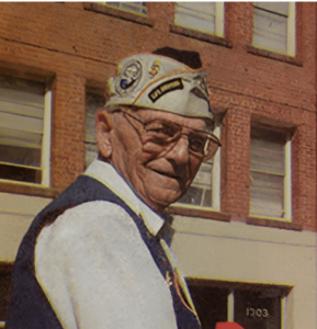 An older photo of Frank, a man wearing large classes and a U.S. Navy cap
