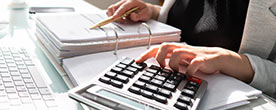 A worker using a calculator and writing in a book