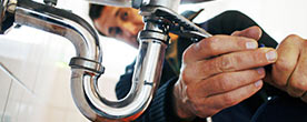 A plumber works on pipes