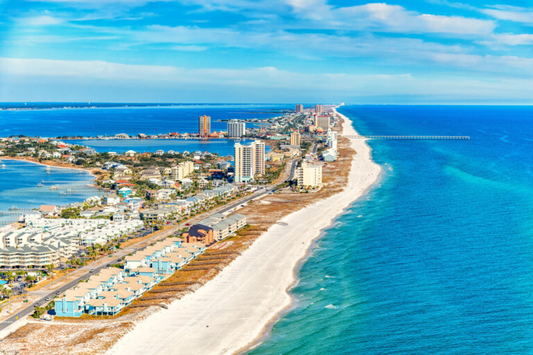 A beach and buildings along the water in Pensacola, FL